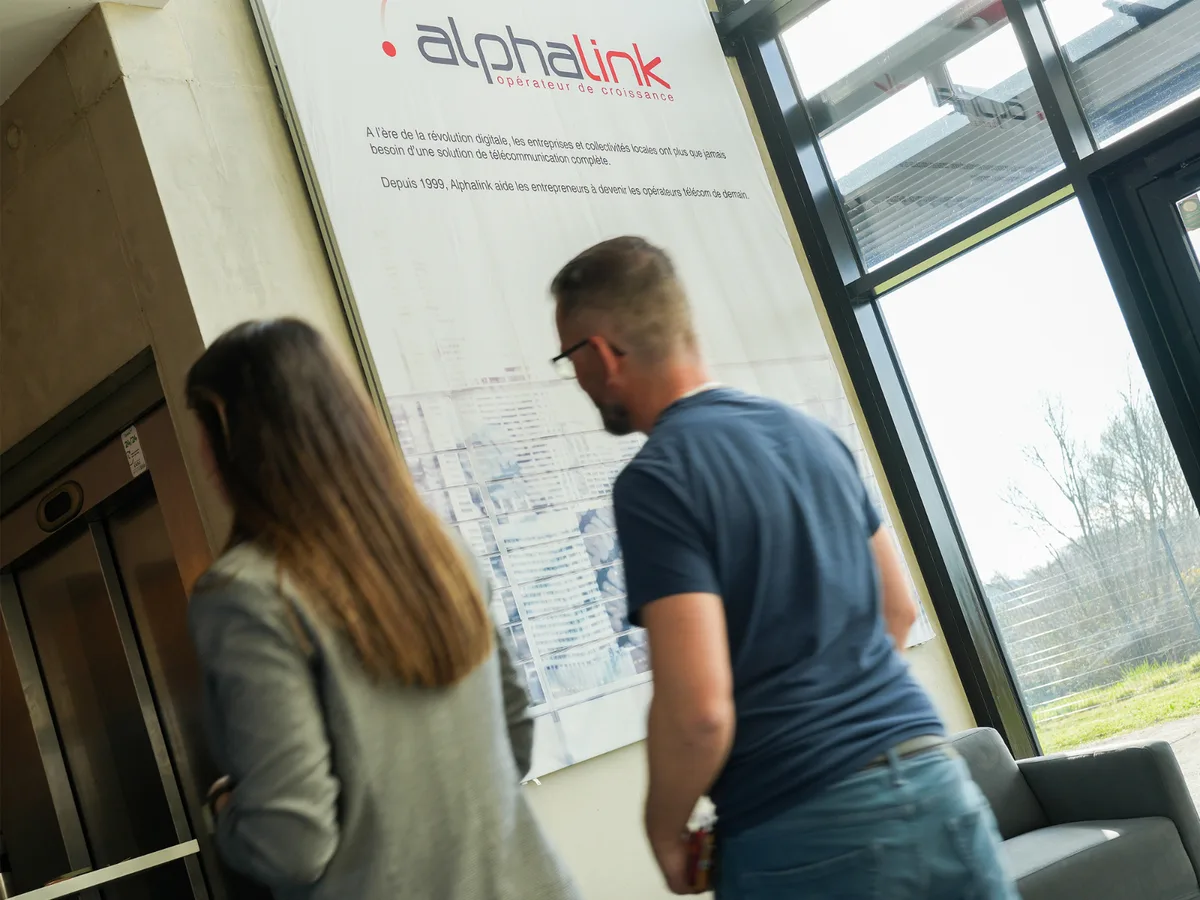 Deux collaborateurs Alphalink devant la carte du réseau, dans le hall de leurs locaux